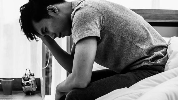 Stres asijský mladý muž sedí sám na posteli. Špatný vztah nebo zkrachovalý problém a koncepce nemoci. - Fotografie, Obrázek
