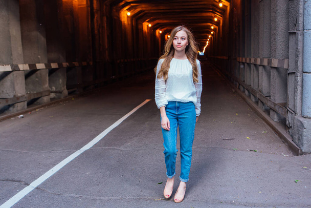 Nuori tyttö pitkät vaaleat hiukset seisoo tumma teollinen tunneli valot - Valokuva, kuva
