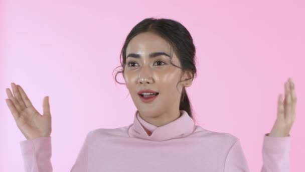 Beauty concept. Beautiful Asian girl opens her eyes with surprise on the pink background. 4k Resolution. - Video
