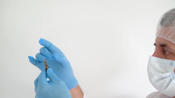 Il medico in maschera medica e guanti apre una fiala di vaccino, primo piano, spazio per la copia - Filmati, video