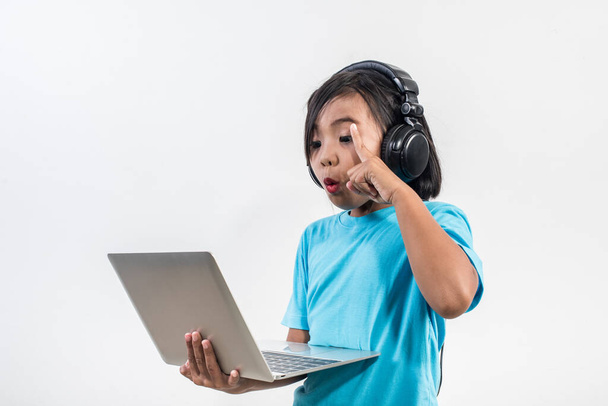 Little girl using laptop computer and listening lesson online  - 写真・画像