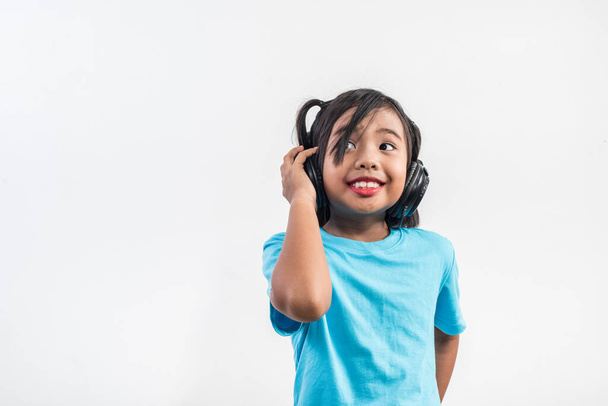 Kleines Mädchen hört Musik über drahtlose Kopfhörer  - Foto, Bild