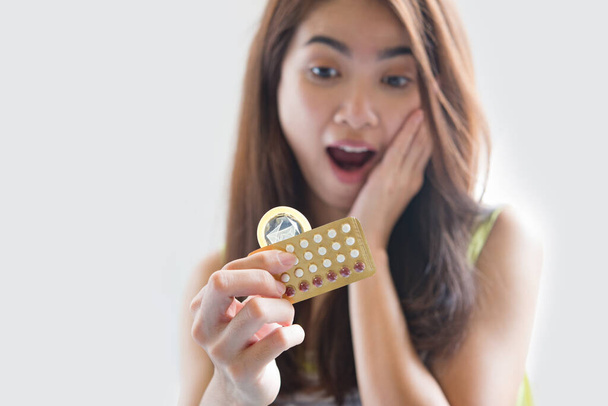 Mujer joven sosteniendo condón y píldoras anticonceptivas previenen el embarazo
 - Foto, Imagen
