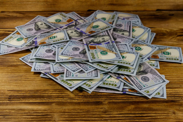 Montón de billetes americanos de cien dólares en un escritorio de madera
 - Foto, imagen