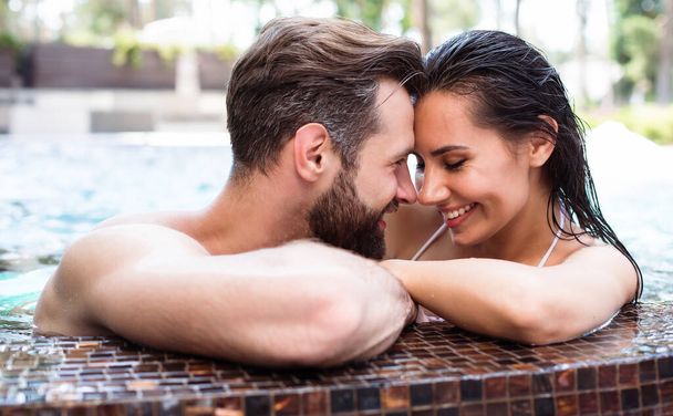 Cheerful couple in love are resting in a swimming pool while summer vacation. - Foto, immagini