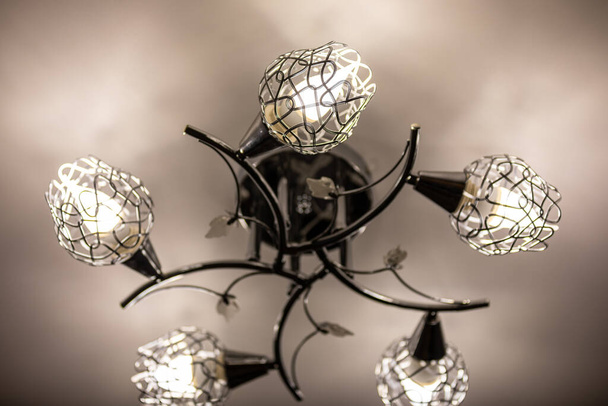 Kovový stropní lustr s pěti odstíny, ve kterém jsou instalovány LED žárovky. Ekonomické osvětlení domu. Koncept úspory energie. - Fotografie, Obrázek