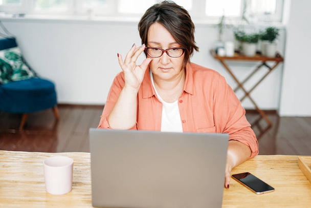 Erwachsene charmante brünette Frau mit Brille plus Größe Körper positive Arbeit mit Laptop im Home Office - Foto, Bild