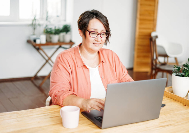 Felnőtt bájos barna nő szemüvegben plusz méret test pozitív dolgozik laptop otthon iroda - Fotó, kép
