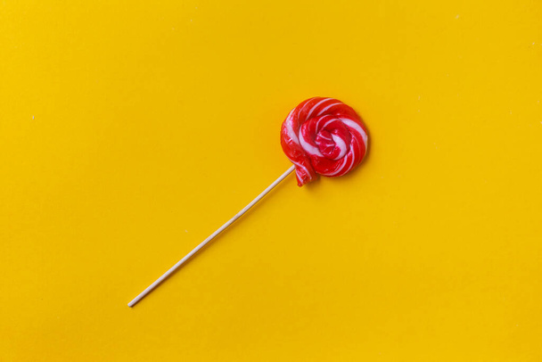 Colorful lollipop on a yellow background. Delicious round candy - Fotoğraf, Görsel