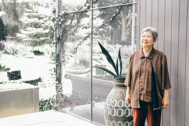 asiatische ältere Frau, die es sich zu Hause auf der Balkonterrasse gemütlich macht. Senioren-Freizeitgestaltung - Foto, Bild