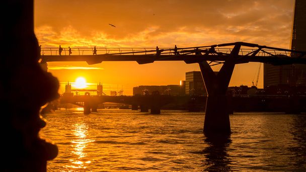 Ранній схід сонця над Містом Тисячоліття і мостом Тауера, коли люди ідуть на роботу. - Фото, зображення