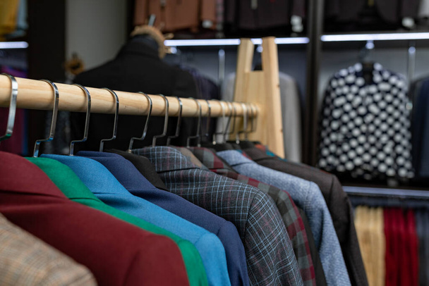loja de roupas cara dos homens. uma linha de jaquetas em cabides. shoping tema de fundo venda. roupas masculinas no cabide na loja
 - Foto, Imagem