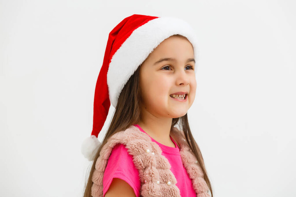 サンタの帽子のかわいいクリスマスの女の子の肖像画、白い背景に隔離された笑顔 - 写真・画像