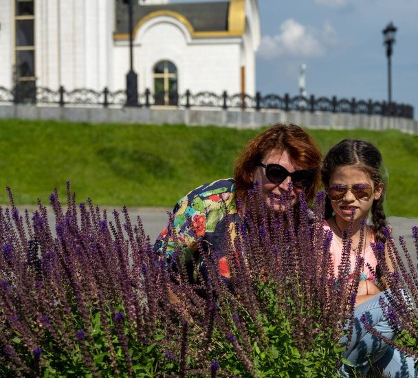 бабуся і онука на фоні фіолетових квітів
 - Фото, зображення