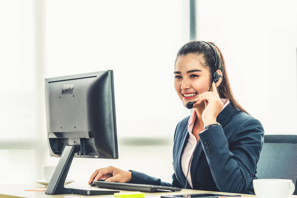 Business people wearing headset working in office to support remote customer or colleague. Call center, telemarketing, customer support agent provide service on telephone video conference call. - Photo, Image