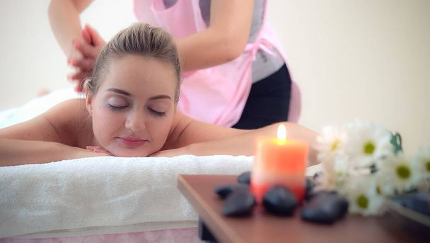 Rahat bir kadın profesyonel masaj terapistiyle lüks kaplıcalarda masaj yaptırıyor. Sağlık, şifa ve rahatlama konsepti. - Fotoğraf, Görsel