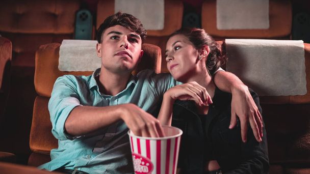 Mannen en vrouwen zijn aan het eten en popcorn gooien was leuk in hun mond in het theater - Foto, afbeelding