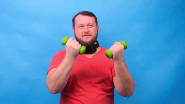 elegante hombre en una camiseta rosa con mancuernas divertido hacer ejercicios sobre un fondo azul
 - Imágenes, Vídeo