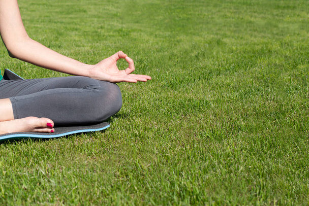 A woman practices yoga outdoors on the grass. Copy space - Photo, Image