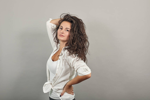 Teen smiling model brushing hand through hair, fashion posing, hands in strand - Fotografie, Obrázek