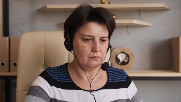 Woman wear headset communicating by conference call speak looking at computer at home office, video chat job interview or distance language course class with online teacher concept - Footage, Video