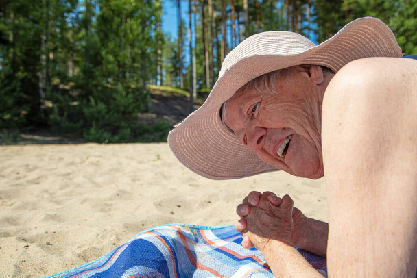 Velha, de chapéu de verão e fato de banho na praia. Ensolarado, dia de verão junto ao mar. Conceito: estilo de vida saudável
 - Foto, Imagem