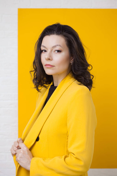 Stylish young woman in a yellow jacket on a yellow background, - Фото, зображення