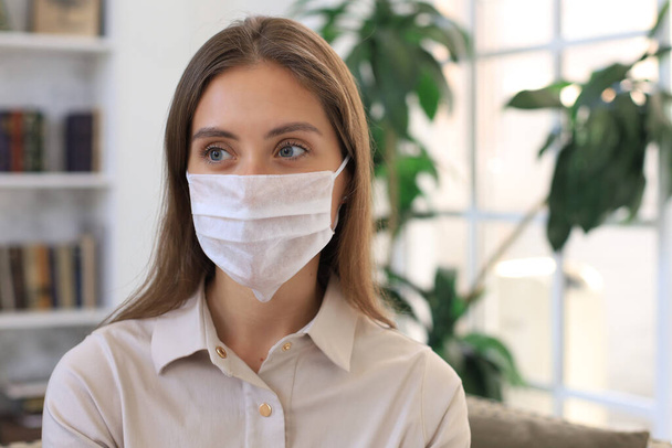 Young woman in medical mask at home during epidemic situation - 写真・画像