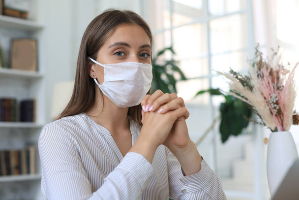 Young woman in medical mask at home during epidemic situation - Фото, изображение