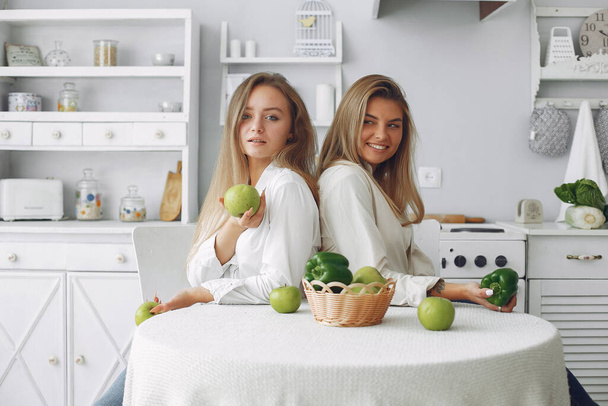 Beautiful and sporty girls in a kitchen with a vegetables - Fotoğraf, Görsel