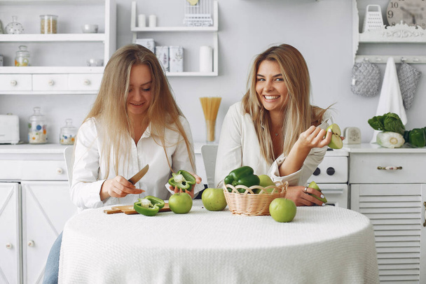 Beautiful and sporty girls in a kitchen with a vegetables - Foto, afbeelding