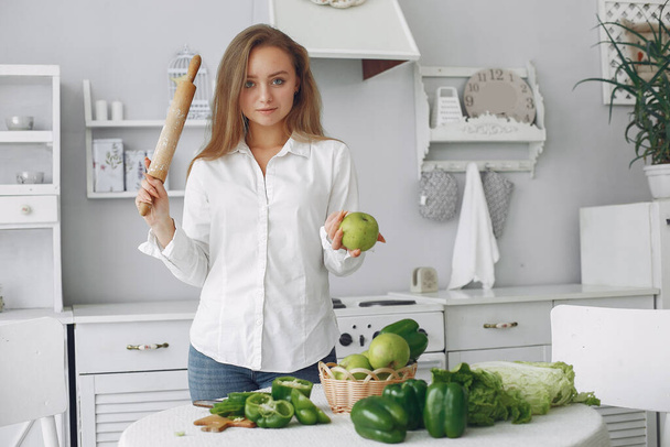 Beautiful and sporty girl in a kitchen with a vegetables - Fotografie, Obrázek