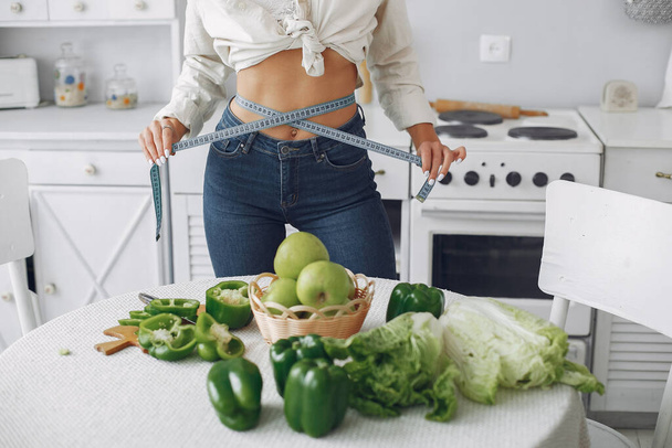 Mooi en sportief meisje in een keuken met een groente - Foto, afbeelding