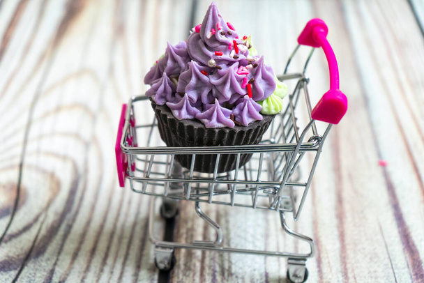 kaunis cupcake jälkiruoka makea saippua sijoitetaan ostoskoriin puinen tausta - Valokuva, kuva