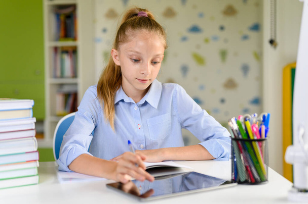 Το κορίτσι διαβάζει και χρησιμοποιεί το τάμπλετ. Κορίτσι μαθήτρια με - Φωτογραφία, εικόνα