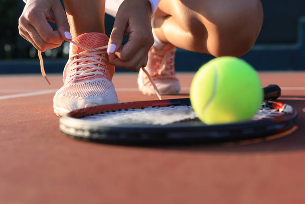 Sports woman getting ready for playing tennis tying shoelaces on outdoor - Foto, afbeelding