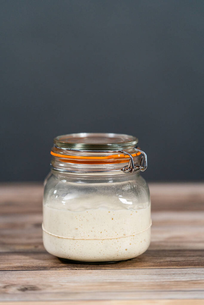 Feeding sourdough starter in a glass mason jar for baking artisan bread. - Photo, Image