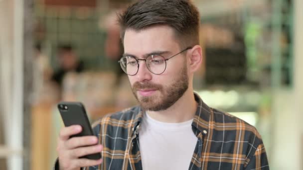 Portrét pozitivního mladého muže pomocí chytrého telefonu  - Záběry, video