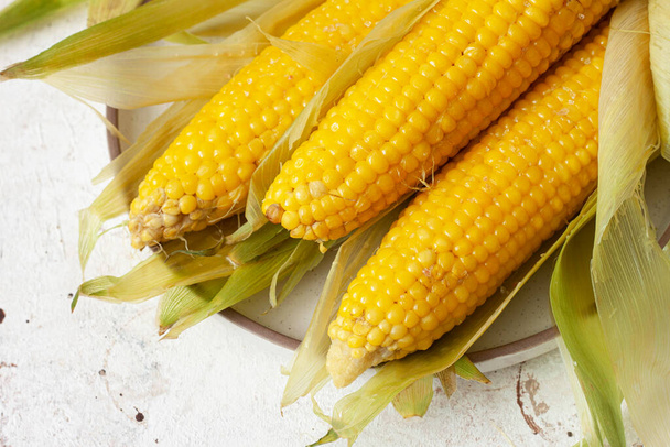 Уши из вареной кукурузы в листьях - Фото, изображение