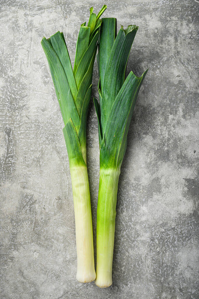 Органічна зелена цибуля з цибулею-пореєм на сірому текстурованому фоні, вид зверху з пробілом для тексту
 - Фото, зображення