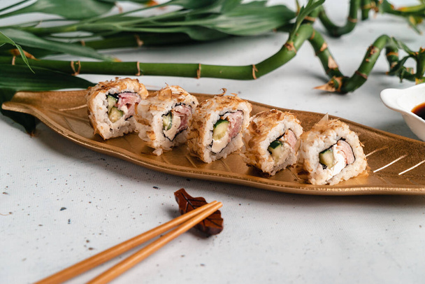 Sushi arany tányéron levél formájában. Japán kaja. Evőpálcika, szójaszósz fehér tálcán. Menü borító. Nézőpont - Fotó, kép