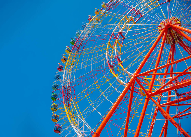 Большое красочное колесо обозрения, изолированное на фоне голубого неба в парке развлечений, расположенном во Вьетнаме, Нячанге, острове Винперл. Летний семейный отдых
.  - Фото, изображение