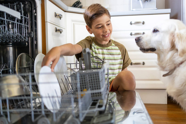 Little boy loading the dishwasher at home - Foto, Imagen