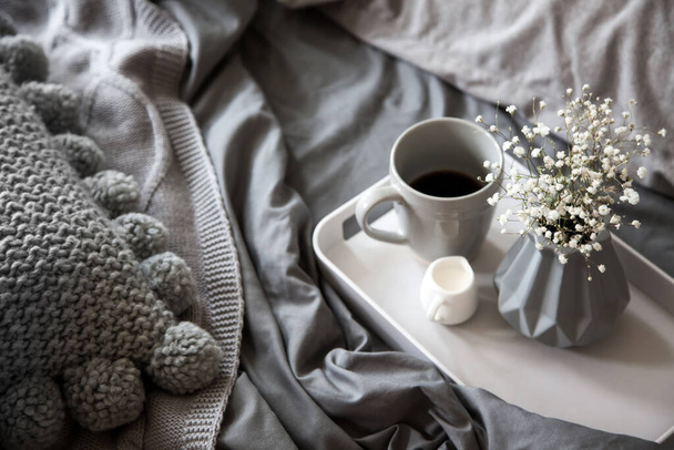 Morning breakfast in bed. Gray bedding. Golden tray in the nordic style. White cup with black coffee and a milkman with milk. Flowers in a gray vase. - Fotoğraf, Görsel