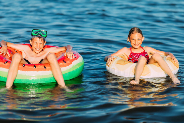 Swimming, summer vacation happy kids boy and girl playing and swimming on the sea with inflatable circles. of summer vacation - Foto, Bild