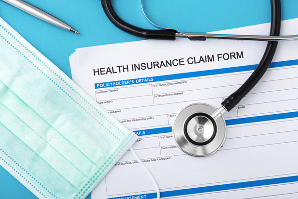 Health insurance claim form with stethoscope and surgical mask, top view - Foto, Imagem