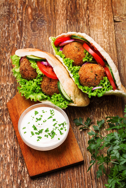Falafel and fresh vegetables in pita bread on wooden table - Foto, Bild