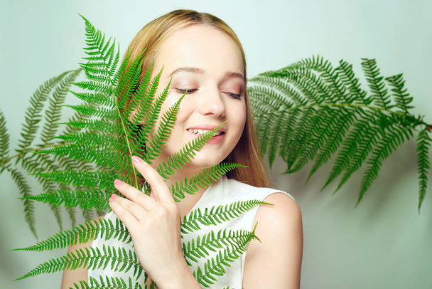 Dívka na pozadí tropické listy přírodní kosmetiky a léků. Model se usmívá a vyzařuje radost - Fotografie, Obrázek