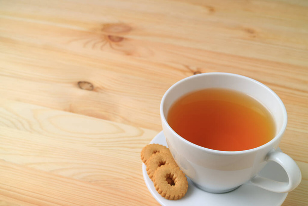 Чашка горячего чая и печенья подается на натуральном деревянном столе, с бесплатным пространством для дизайна и текста
 - Фото, изображение