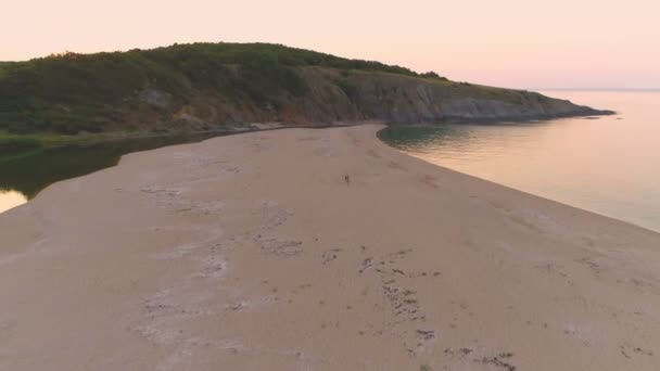 Ζευγάρι περπατά σε στενή λωρίδα άμμου μεταξύ ποταμού και θάλασσας στο ηλιοβασίλεμα στο Σινεμορέ της Βουλγαρίας - Πλάνα, βίντεο